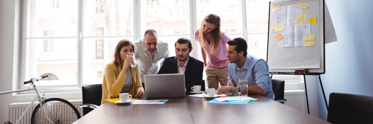 4 Personen sitzen vor Laptop und besprechen etwas