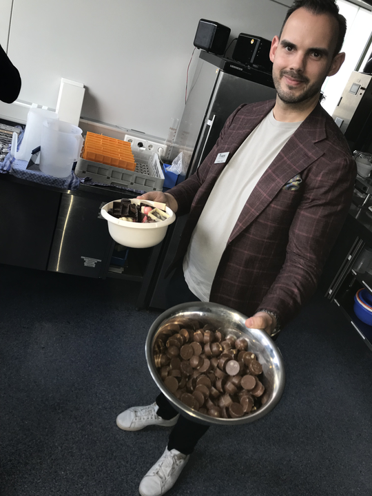 Mitarbeiter bietet Schokolade aus der Produktion an