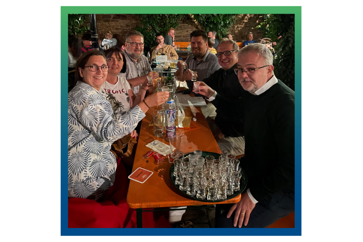 Sechs IHK-Kollegen sitzen an einer Bierbank und stoßen auf ihren Siegt bei einem Quizturnier an.