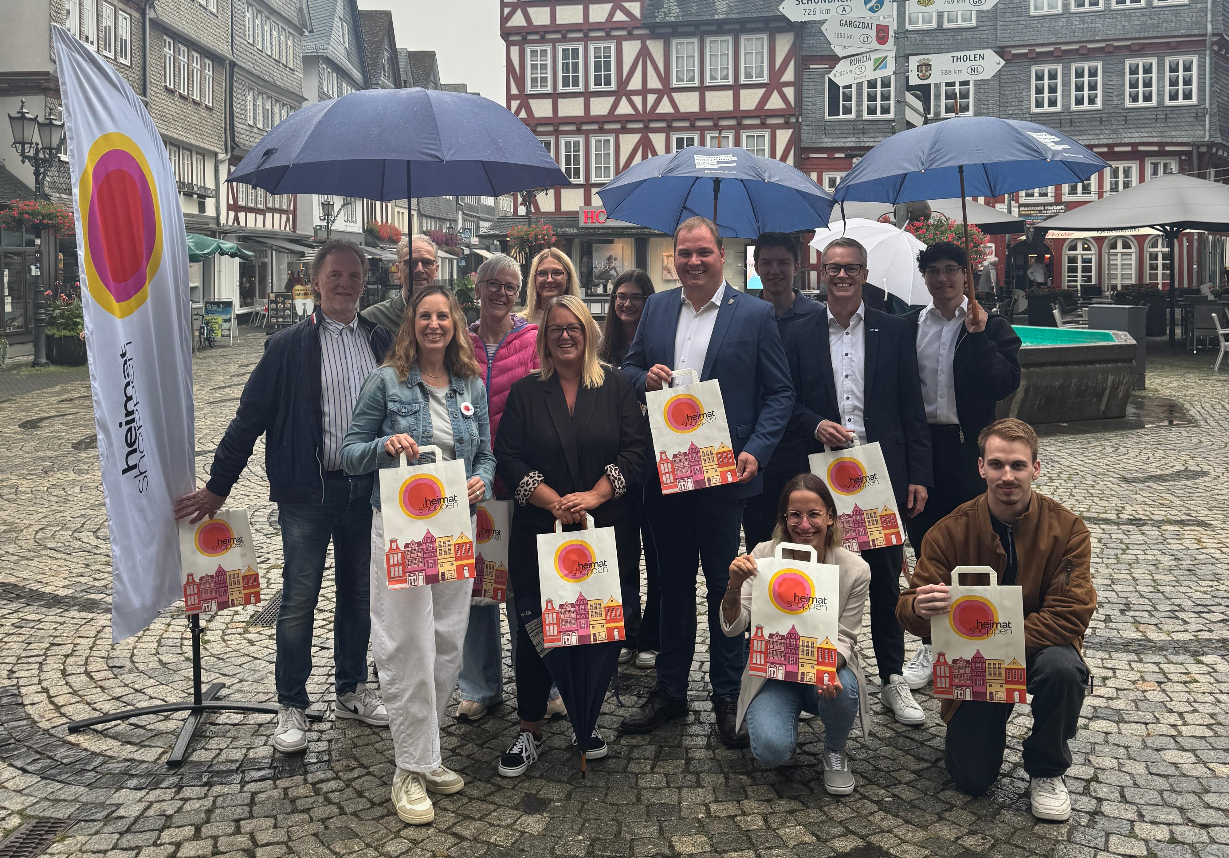 Teilnehmende der Aktion ‚Heimat shoppen‘ auf dem Herborner Marktplatz vor historischen Fachwerkhäusern.