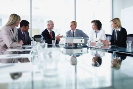 Geschaeftsleute sitzen in einer Besprechung am Tisch