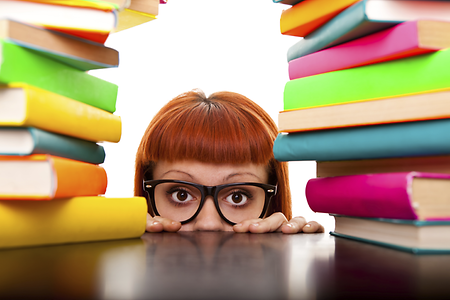 Junge Frau verschwindet hinter Bücherstapel