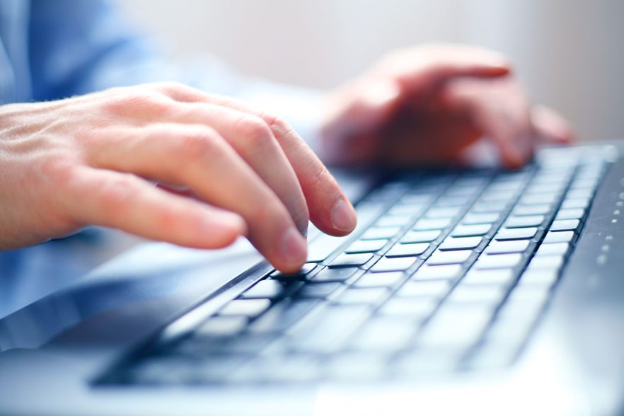 Eine Person tippt auf der Tastatur eines Laptops.
