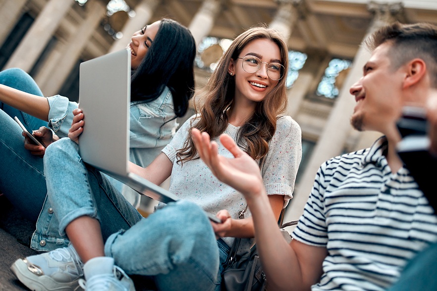 Schülerinnen und Schüler sitzen zusammen, Laptop auf dem Schoß