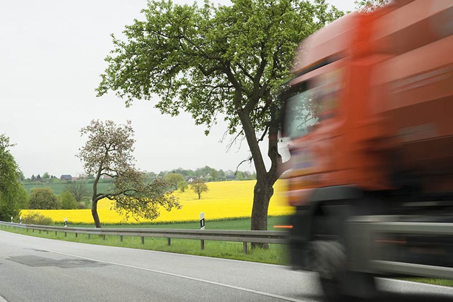 LKW jagt über die von Rapsfeldern gesäumte Landstrasse