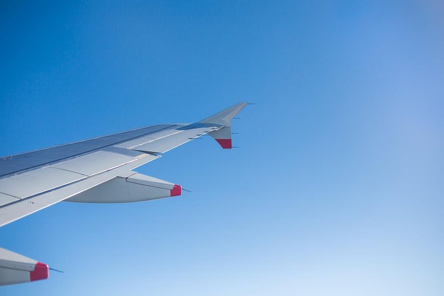 Man sieht den rechten Fl&uuml;gel eines fliegenden Flugzeuges aus der Sicht eines Passagieres.