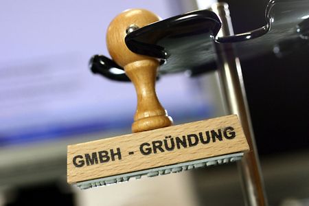 Ein Stempel mit der Aufschrift GmbH-Gr&uuml;ndung steht auf einem Tisch.