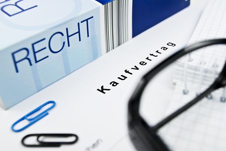 Ein Kaufvertrag liegt neben einem Ordner mit der Aufschrift Recht.