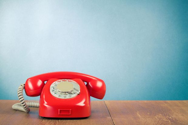 Ein rotes Telefon steht vor einer blauen Wand