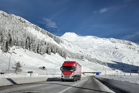 Lkw f&auml;hrt auf einer Stra&szlig;e durch eine Winterlandschaft.