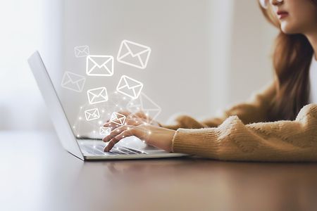 Frau, die einen Laptop benutzt und eine E-Mail mit E-Mail-Symbol versendet