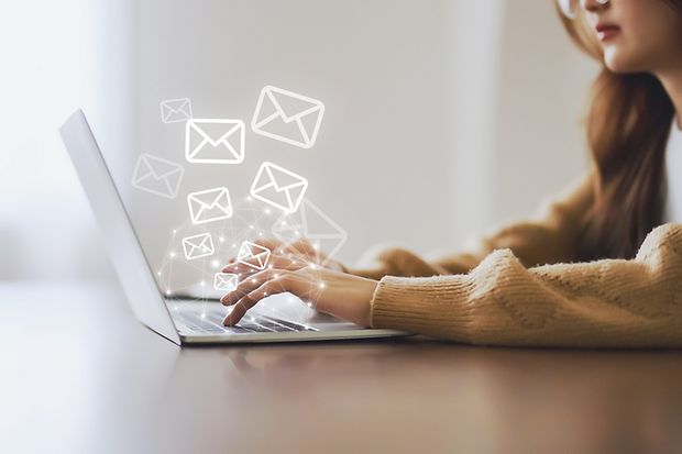 Frau, die einen Laptop benutzt und eine E-Mail mit E-Mail-Symbol versendet