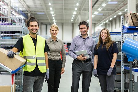 Azubis mit ihrer Chefin in einer Lagerhalle
