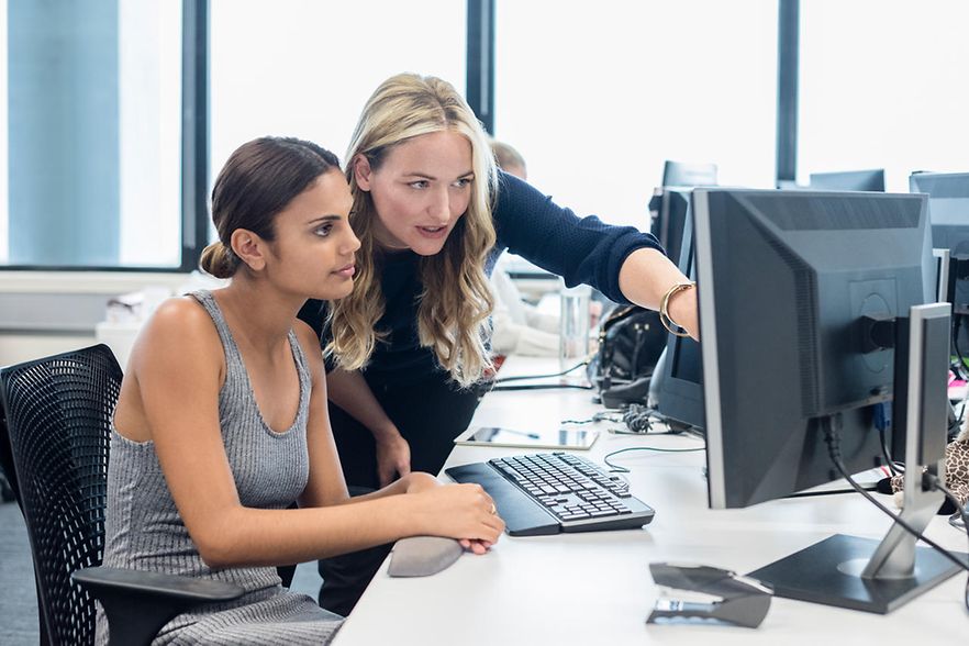 Zwei Frauen arbeiten gemeinsam am Computer in einem modernen B&uuml;ro.