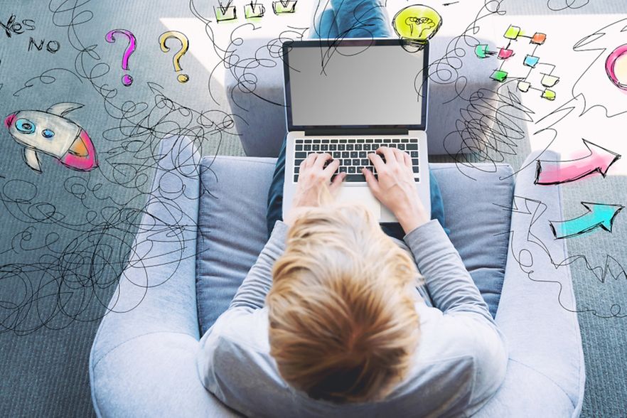 Jugendlicher sitzt mit seinem Laptop auf dem Sessel und tippt etwas ein