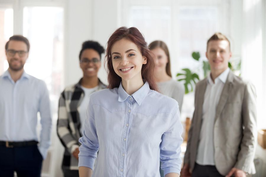 Portrait of smiling female employee foreground posing for picture