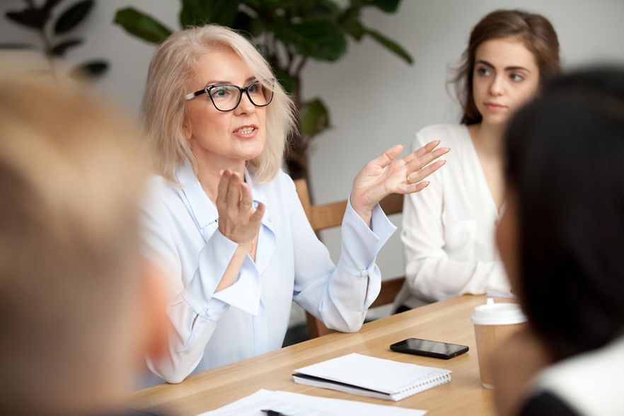 Frau gestikuliert am Tisch