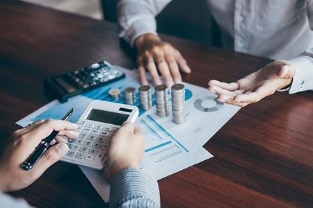 Finanzberatung mit Rechner, Diagrammen, Euro-Scheinen und M&uuml;nzen.