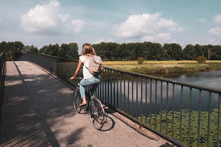 Eine Fahrradfahrerin &uuml;berquert eine Br&uuml;cke.