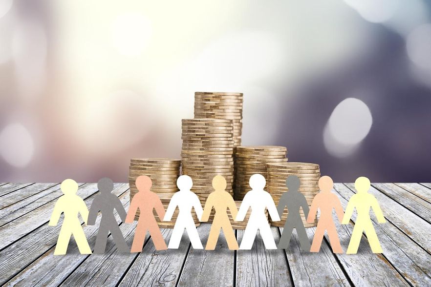 Papierfiguren vor Geldstapel