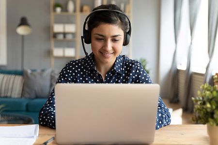 Smiling millennial ethnic female watch webinar on computer