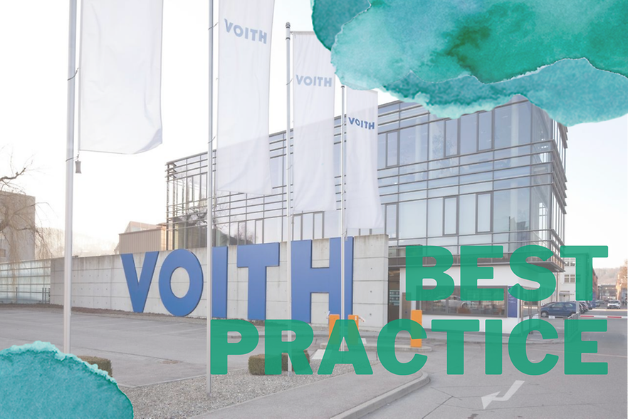 Voith-Best Practice als Schrift in blau und grün, weiße Fahnen mit Aufschrift Voith, im Hintergrund Mauer und Gebäude 