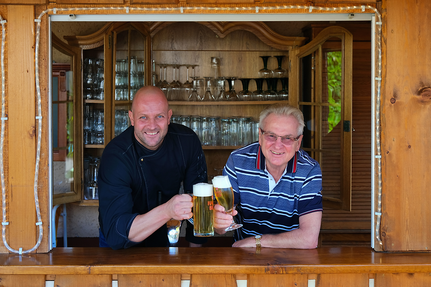 Zwei Männer stoßen mit einem Glas Bier an