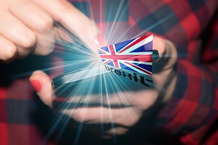 Frau mit Smartphone mit dem Schriftzug Brexit und einer britischen Flagge