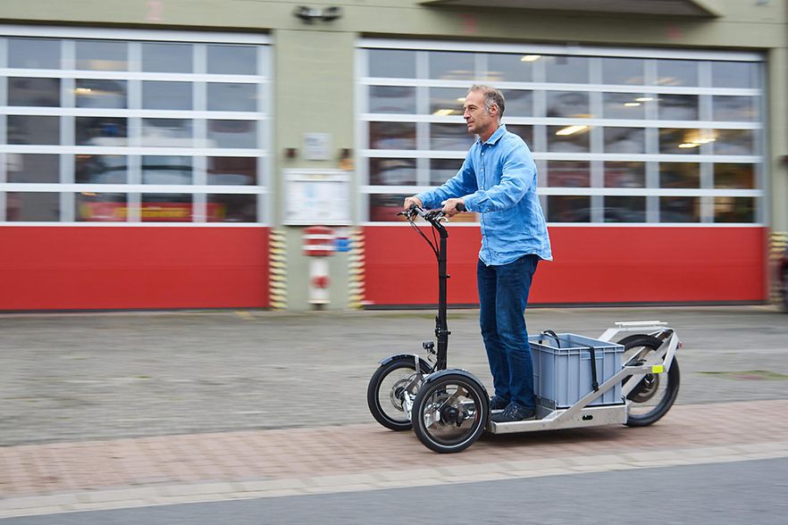 M&auml;nnliche Person f&auml;hrt mit einem elektrischen Lastenroller