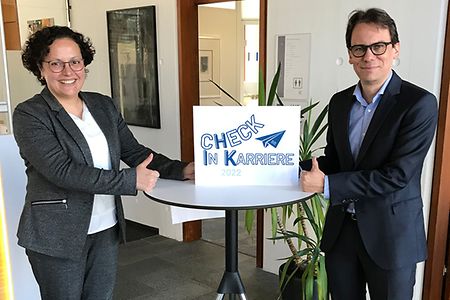 Marion Oker und Tilo Ambacher mit Schild Check in Karriere