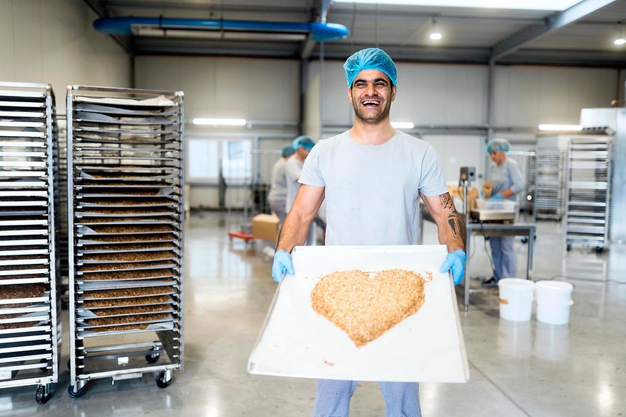 Milad von HEYHO h&auml;lt ein Backbleck vor sich, auf dem Cerealien zu einem Herz geformt sind