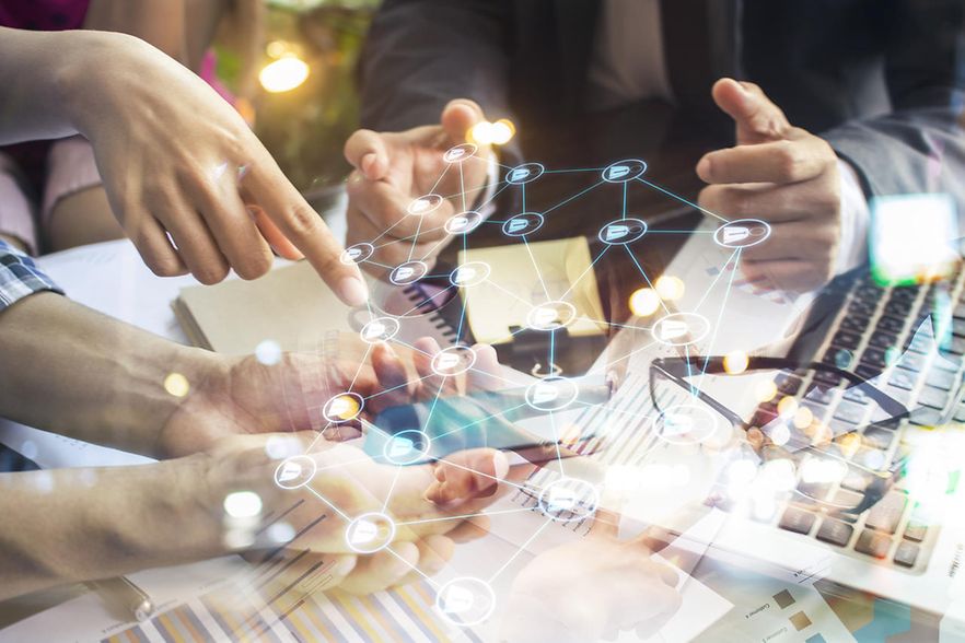 Digitalisierungssymbole, im Hintergrund Personen mit Laptop und Handy