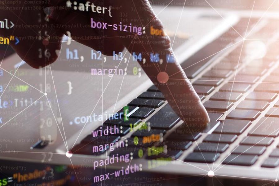 Tastatur mit Hand sowie Computer-Quellcode
