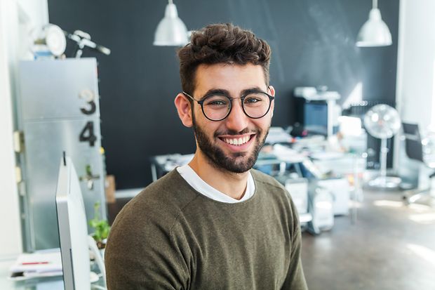 Ein junger Mann mit Brille lächelt in die Kamera