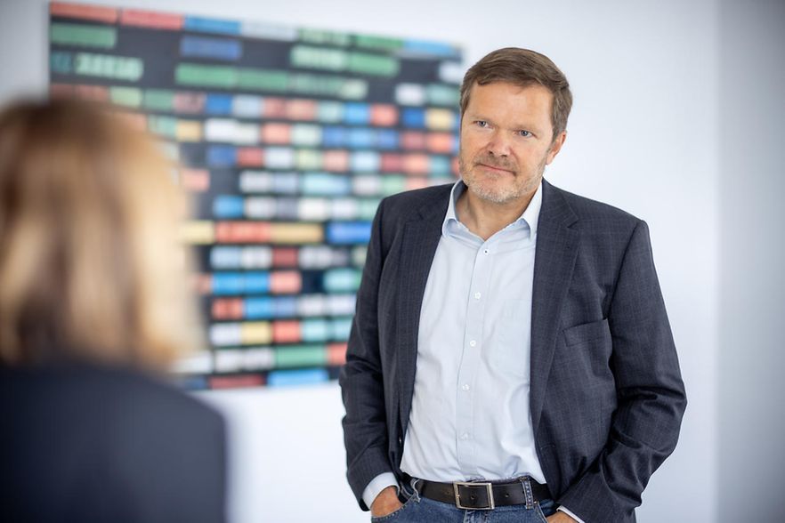 S&ouml;nke Feldhusen steht in einem Raum, vor ihm unscharf eine Frau.
