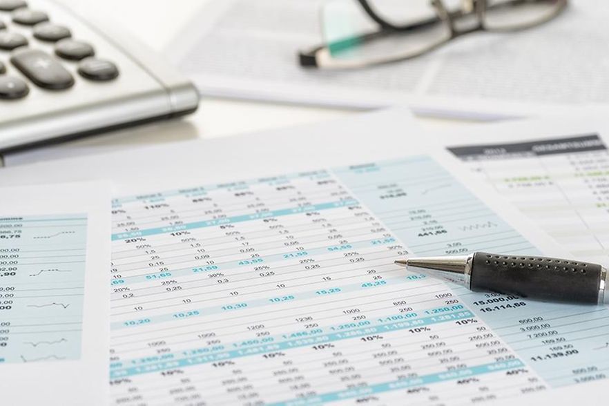 Auf einem Schreibtisch liegen Datenbl&auml;tter, ein Taschenrechner und ein Stift