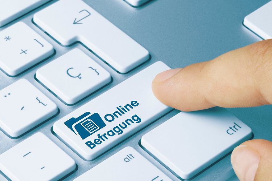 Computertastatur mit einer Taste auf der steht "Online-Befragung", die von einem Zeigefinger gedr&uuml;ckt wird