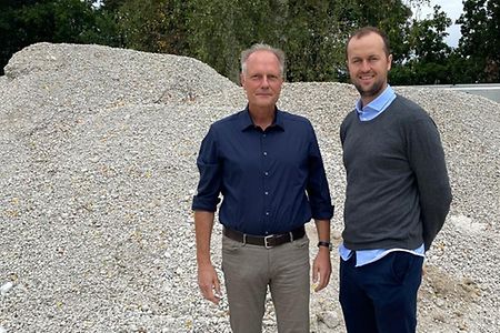 Volker Witt und Lorenz K&auml;hler stehen vor einem Kiesberg.