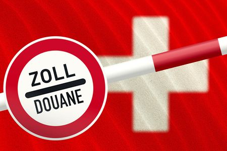 Zollschild an einem Schlagbaum, im Hintergrund die Schweizer Fahne (wei&szlig;es Kreuz auf rotem Hintergrund).
