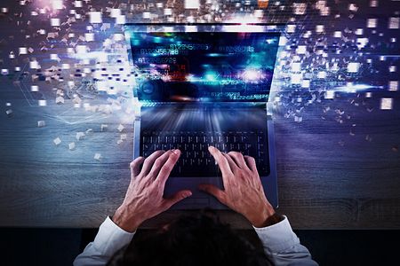 Mann am Laptop, Datenstrom wird durch Lichteffekte symbolisiert