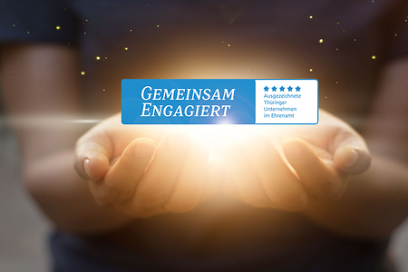 Zwei geöffnete Hände sind hell erleuchtet. Darüber schwebt ein Logo mit dem Schriftzug „Gemeinsam engagiert".