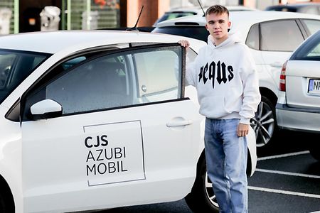 &bdquo;Ein Azubi steigt in das firmeneigene Azubi-Mobil ein.&ldquo;