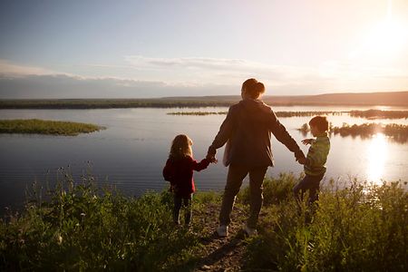 Mom,And,Two,Kids,Walk,Near,The,River.,Social,Distancing.
