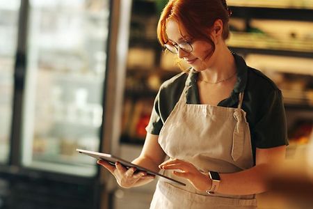 Happy,Supermarket,Owner,Using,A,Digital,Tablet,While,Standing,In