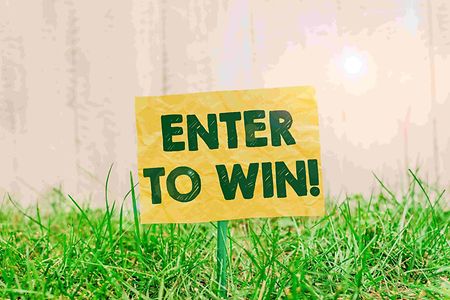 Gelbes Schild mit der Aufschrift "Enter to win" steck in einer gr&uuml;nen Wiese