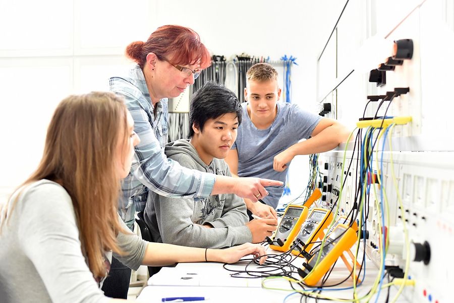 Auf dem Bild sind vier Personen zu sehen, die an etwas arbeiten.