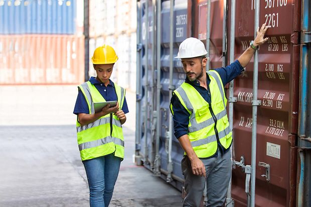 Hafenarbeiter und Vorgesetzte kontrollieren Container im Hafen. 