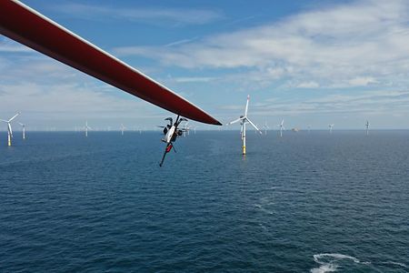 Eine Drohne dockt an ein Rotorblatt einer Offshore- Windkraftanlage an.