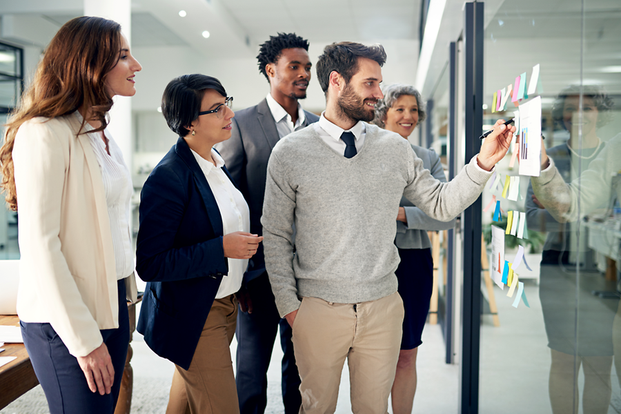 Menschen stehen im Büro vor einer Infowand mit Notizen
