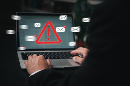 Mann benutzt Notebook, auf dessen Bildschirm eine Warnung erscheint